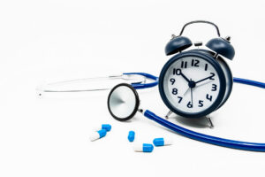 A stethoscope, clock and blue capsules with nedicine